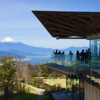 From Yume terrace deck,the iconic Mt.Fuji stands tall under a clear blue sky.Its snow-capped peak sharply defined,the silhouettes of several people are visible,their figures dark against the bright scenery as they stand in awe,gazing at the nountain.