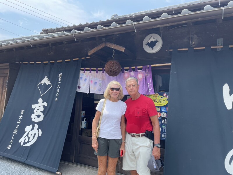 Foreign couple posing in front of the noren curtain at Takasago Sake Brewery in Fujinomiya.


