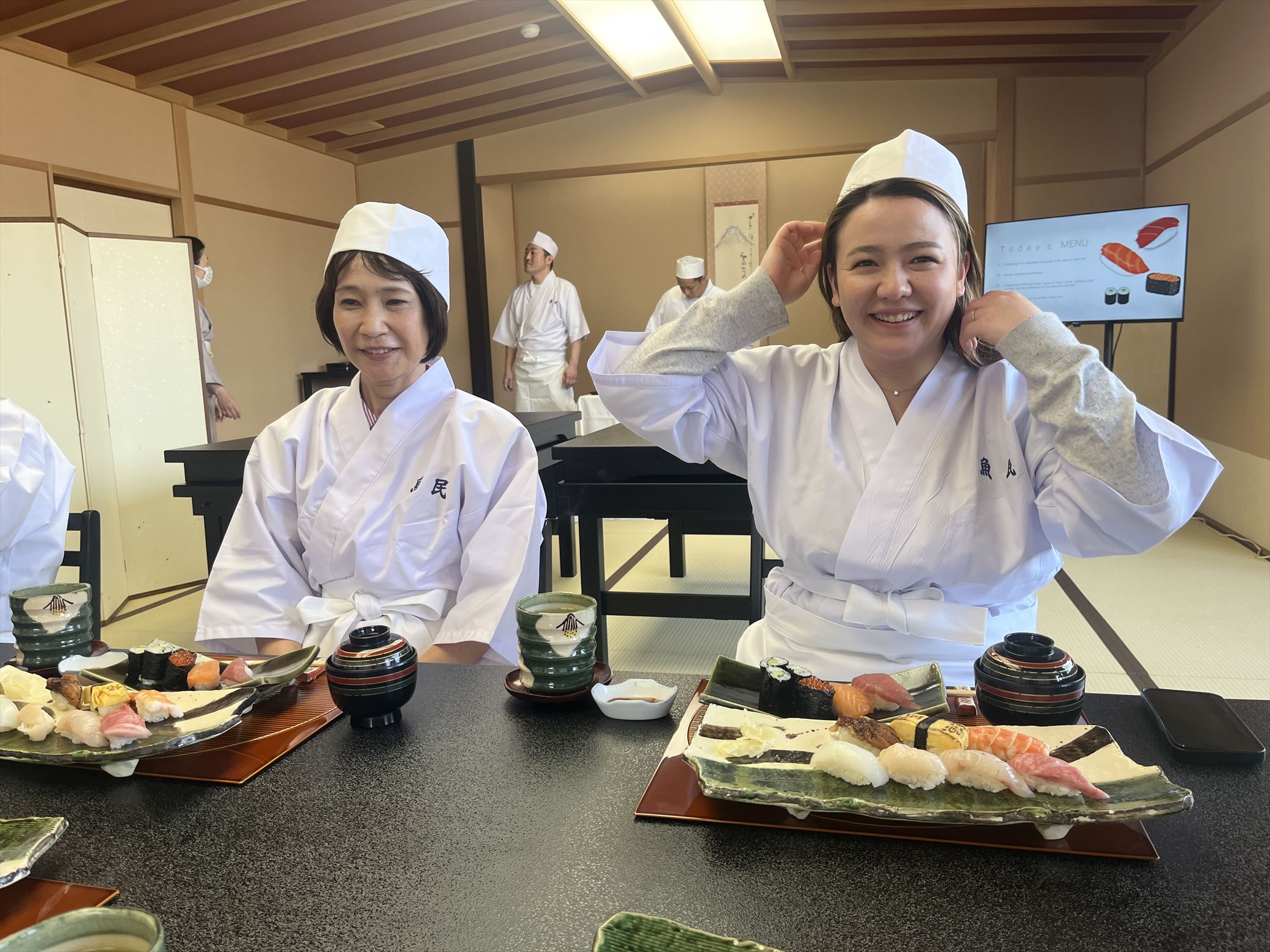 Two reraxed staff members tasting and comparing their own handmade sushi with sushi made by professional chefs.
