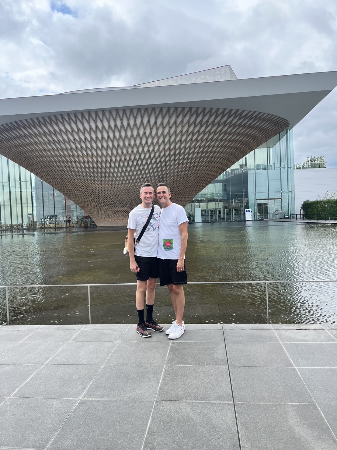 A smiling couple posing in front of the modern Mt. Fuji World Heritage Center building.