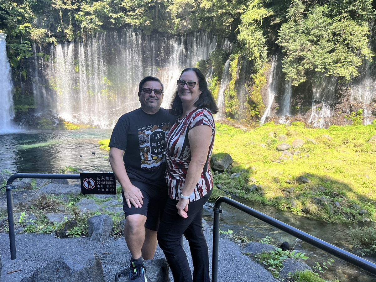 Happy couple posing in front of Shiraito Falls.
