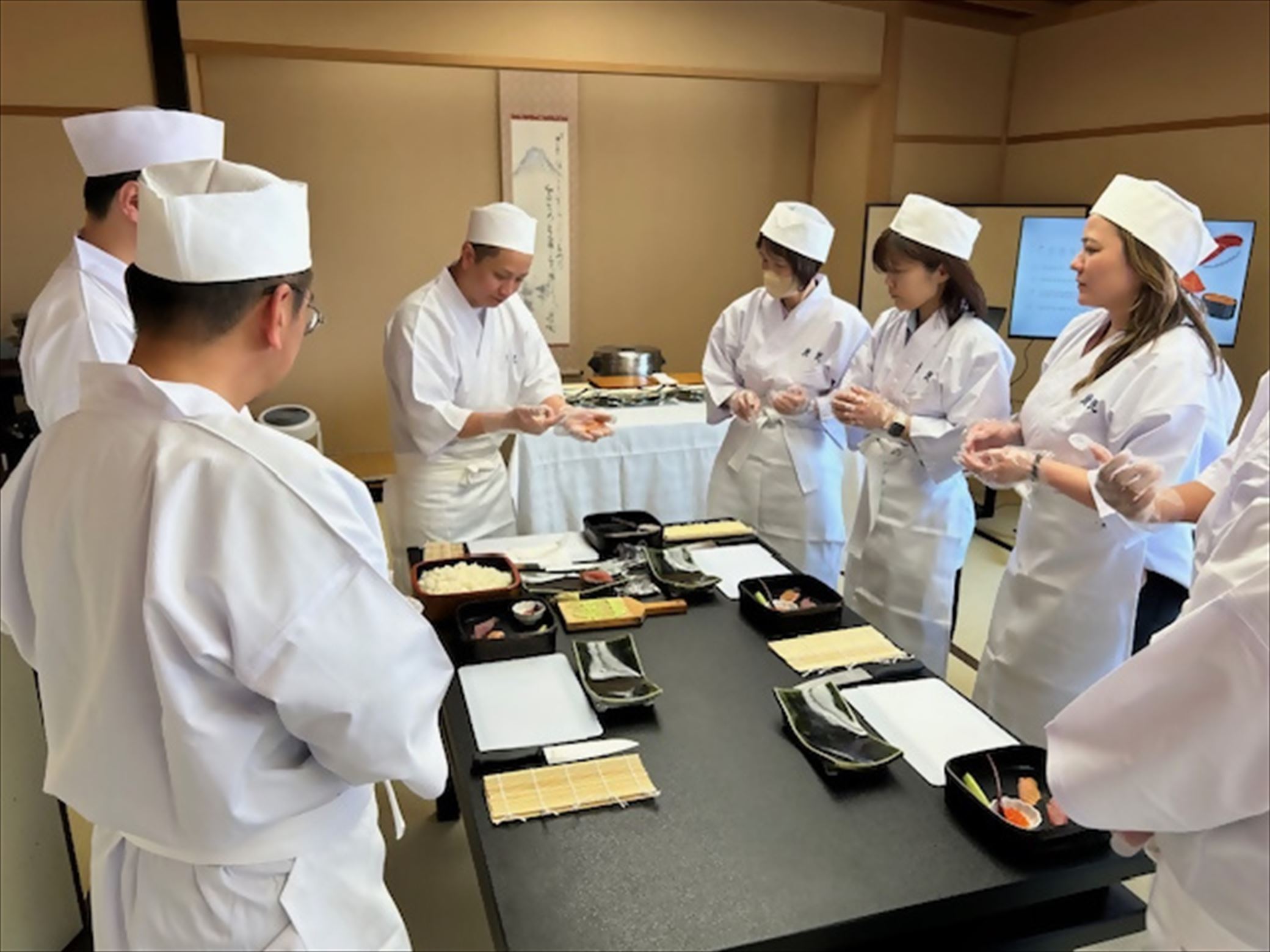 Participants wearing white sushi shef coats,making sushi during a hands-on experience in Fuji City.