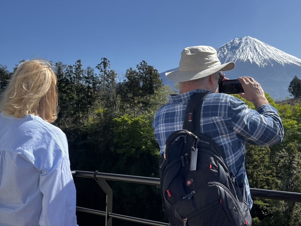 Tourist couple viewing Mt. Fuji with binoculars from Shiraito Falls.

