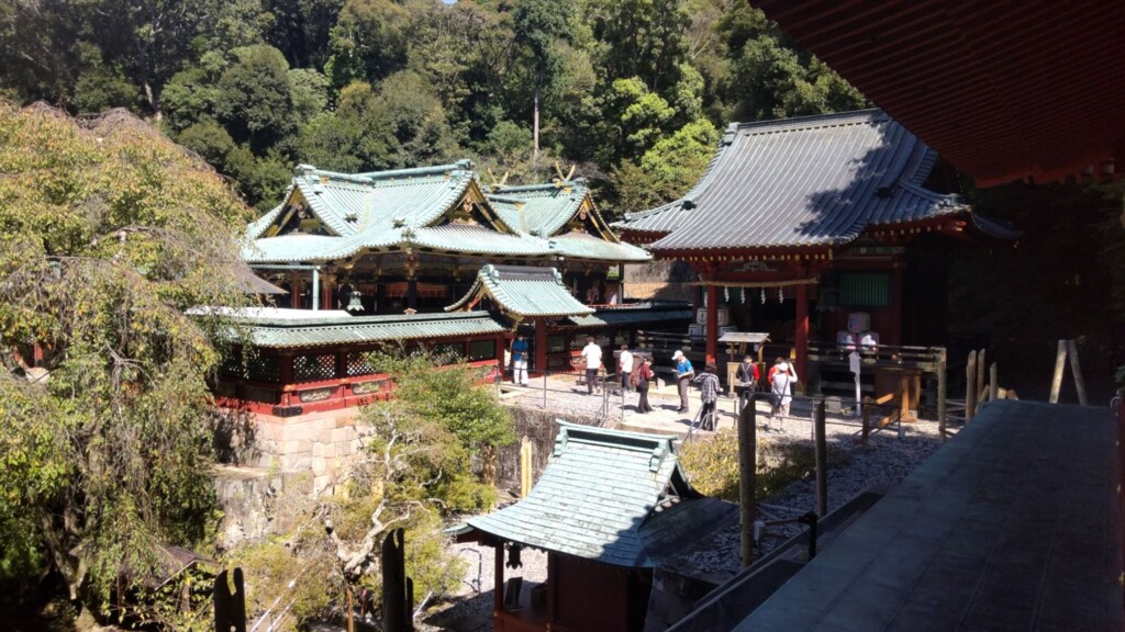 Distant view of the ornate main shrine at Kunozan Toshogu, showcasing traditional Gongen-zukuri architecture surrounded by greenery.