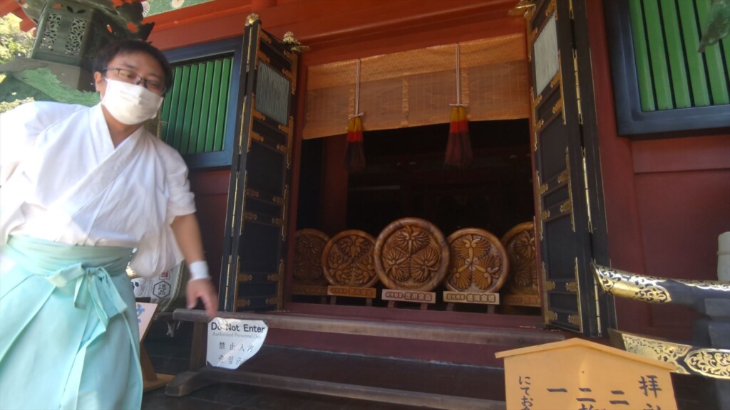 Shinto priest guiding visitors inside Hie Shrine at Kunozan Toshogu, Shizuoka, explaining the site's history and former role as a Buddhist hall.the sacred building while introducing the history and relationship between Yakushi Nyorai and the Reformation.