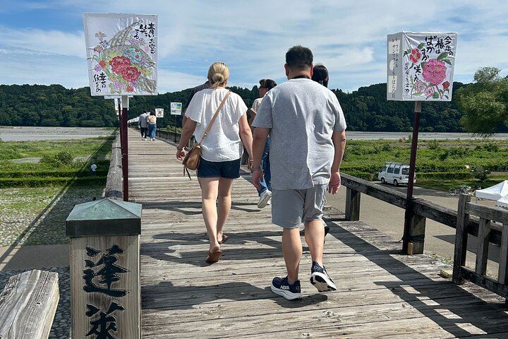 Back view of tour participants walking across the 897.4-meter-long Horai Bridge in Shimada, known for bringing good fortune halfway across.