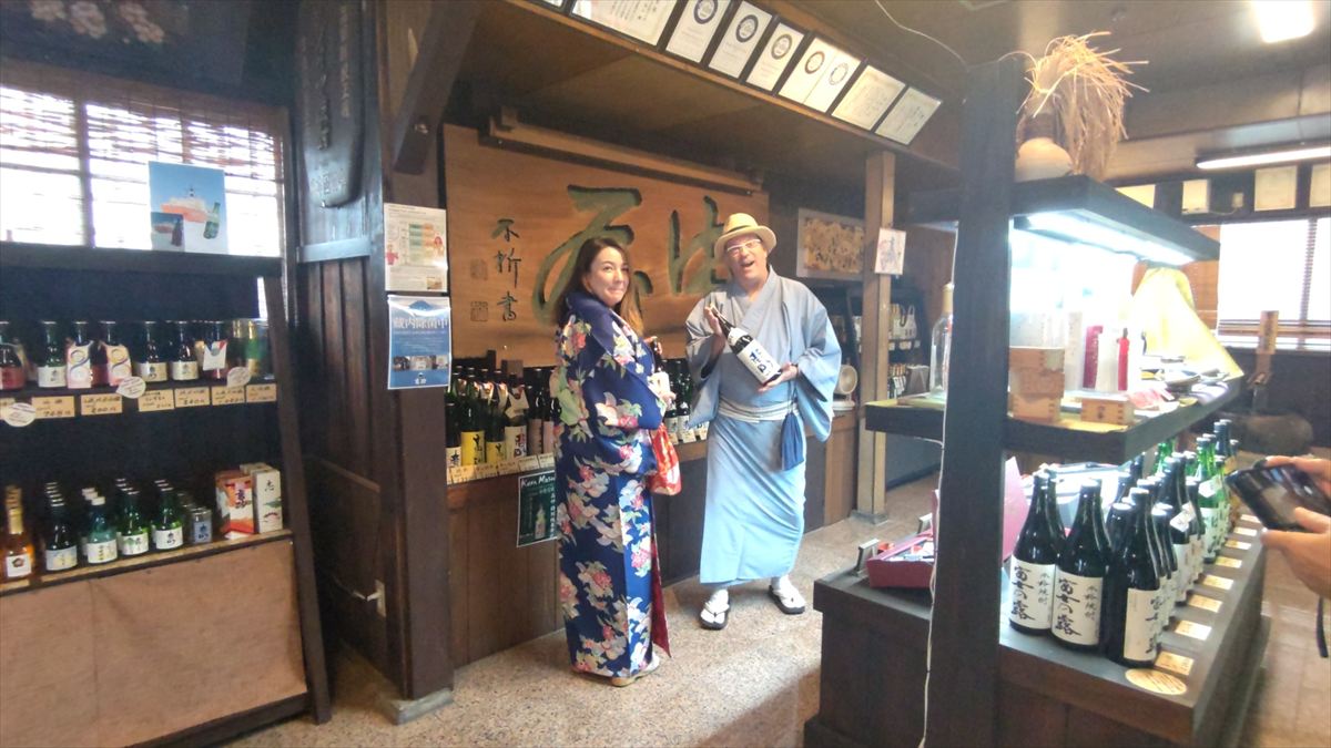 Man and woman in kimono browsing sake selections at Takasago Brewery.