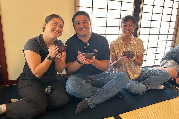 Three Hawaiian visitors holding matcha tea together during a Japanese tea ceremony on a cultural tour in Shimada.


