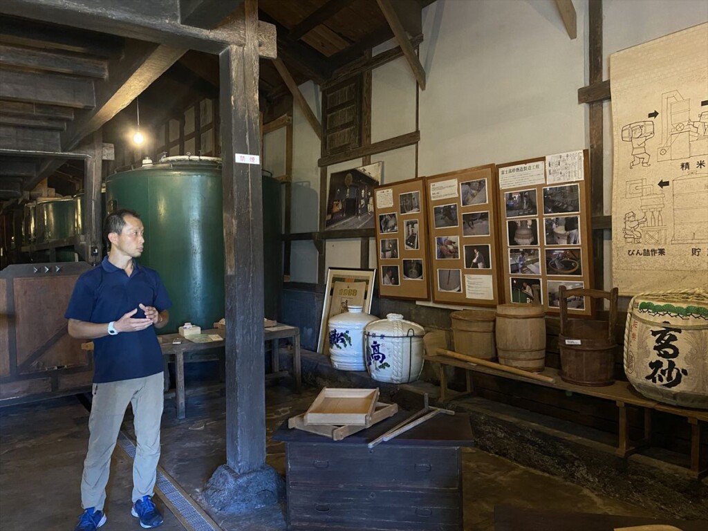 English-speaking staff member explaining the sake brewing process at Takasago Brewery.

